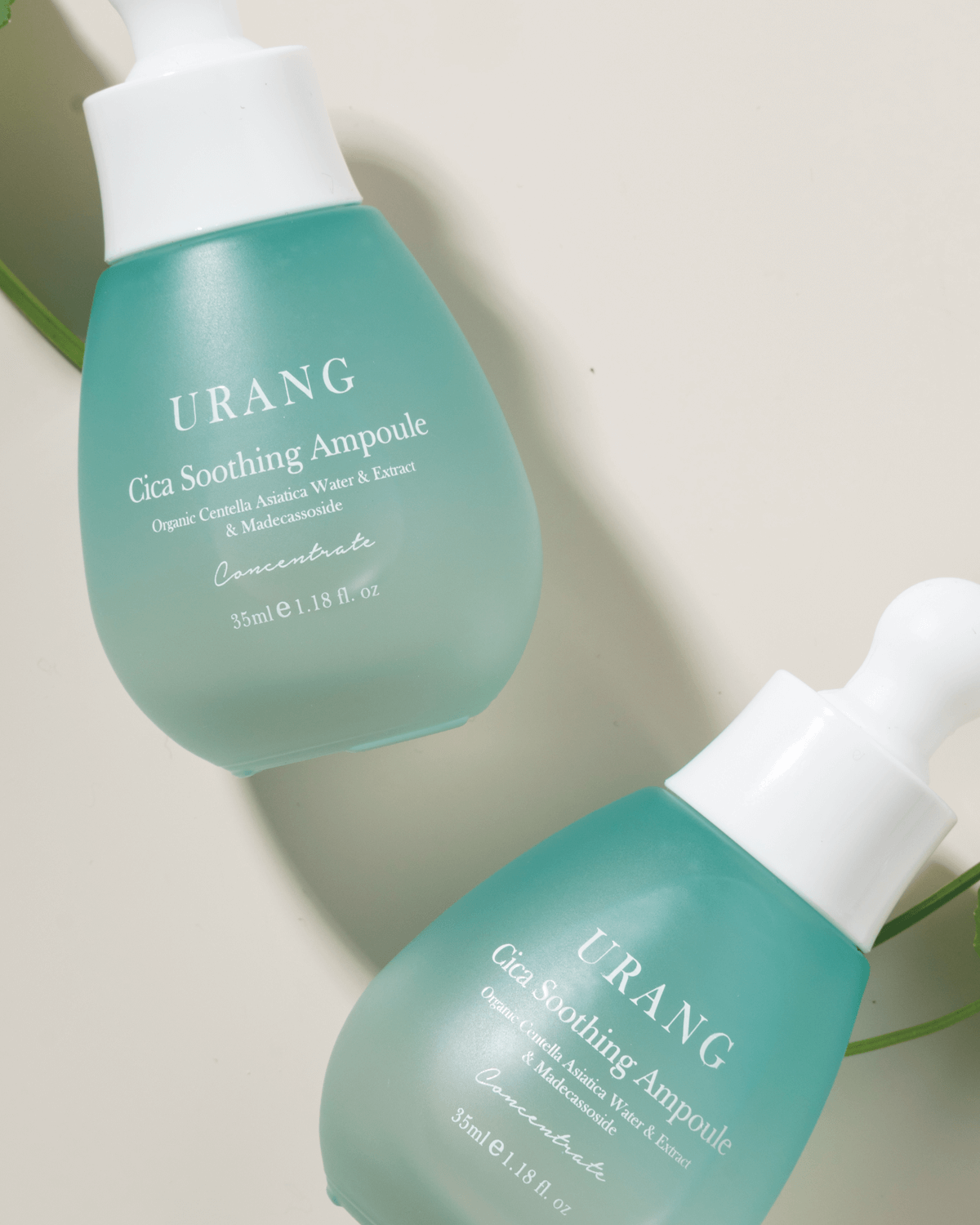 Two bottles of Urang Cica Soothing Ampoule, showcasing the light green color and its concentrated Centella Asiatica formula that soothes and repairs sensitive, delicate skin.