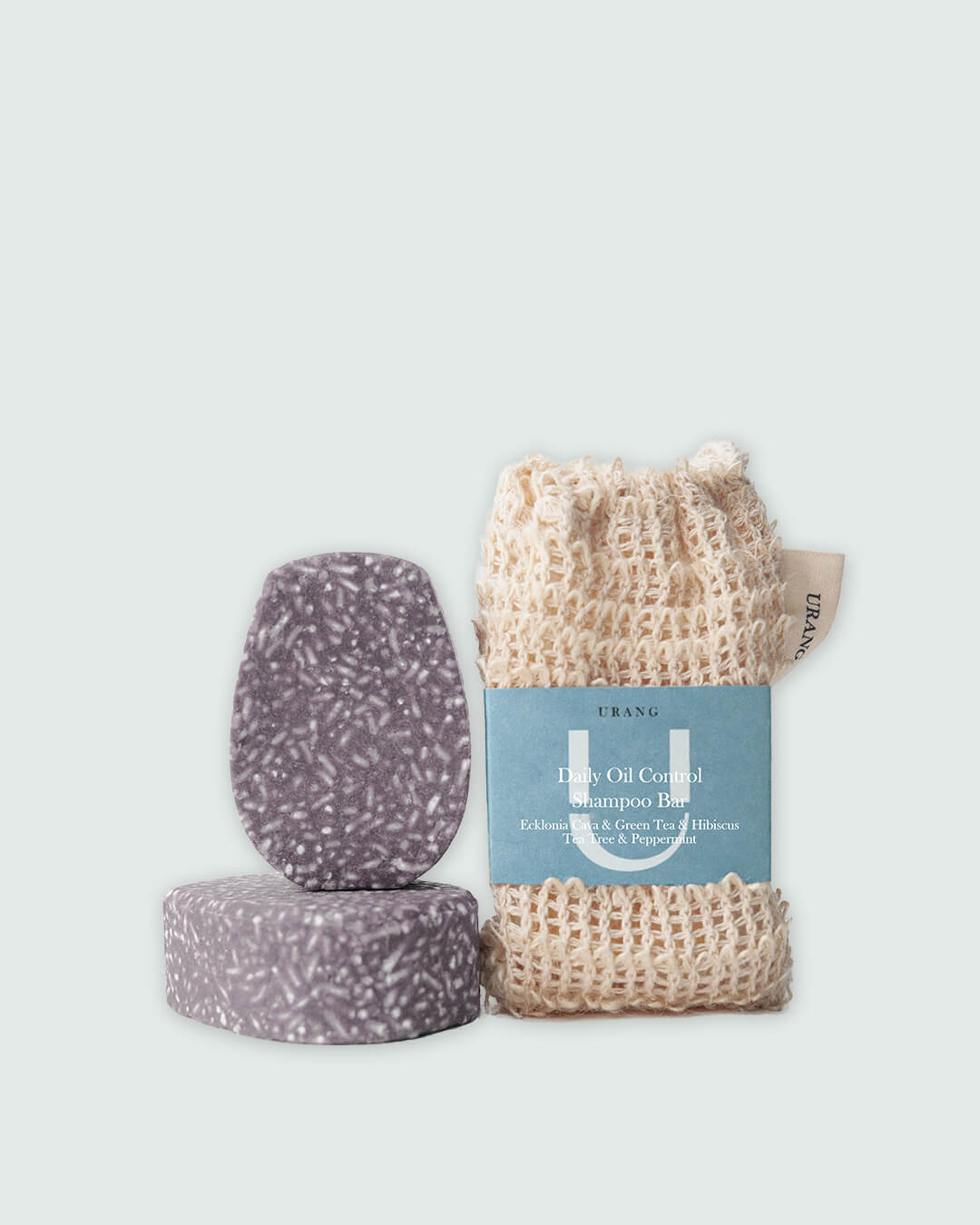 Two Urang Daily Oil Control Shampoo Bars next to a foaming net, emphasizing the solid, plastic-free format that removes excess oil and balances the scalp.