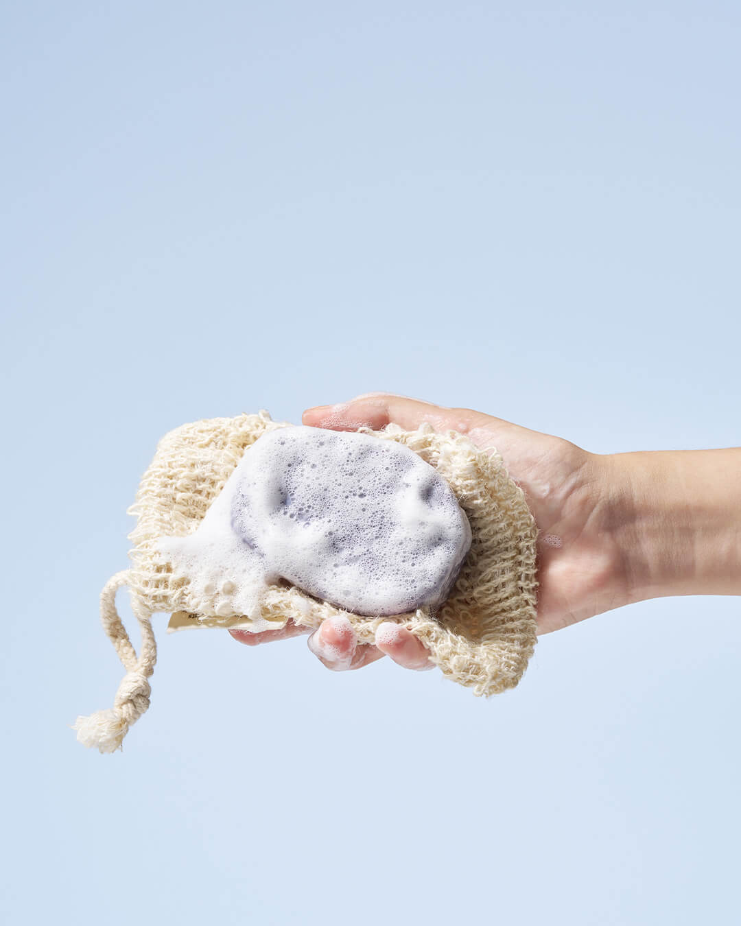 Hand lathering the Urang Daily Oil Control Shampoo Bar with a cleansing net, showing the rich, bubbly foam that controls oil and clarifies the scalp.