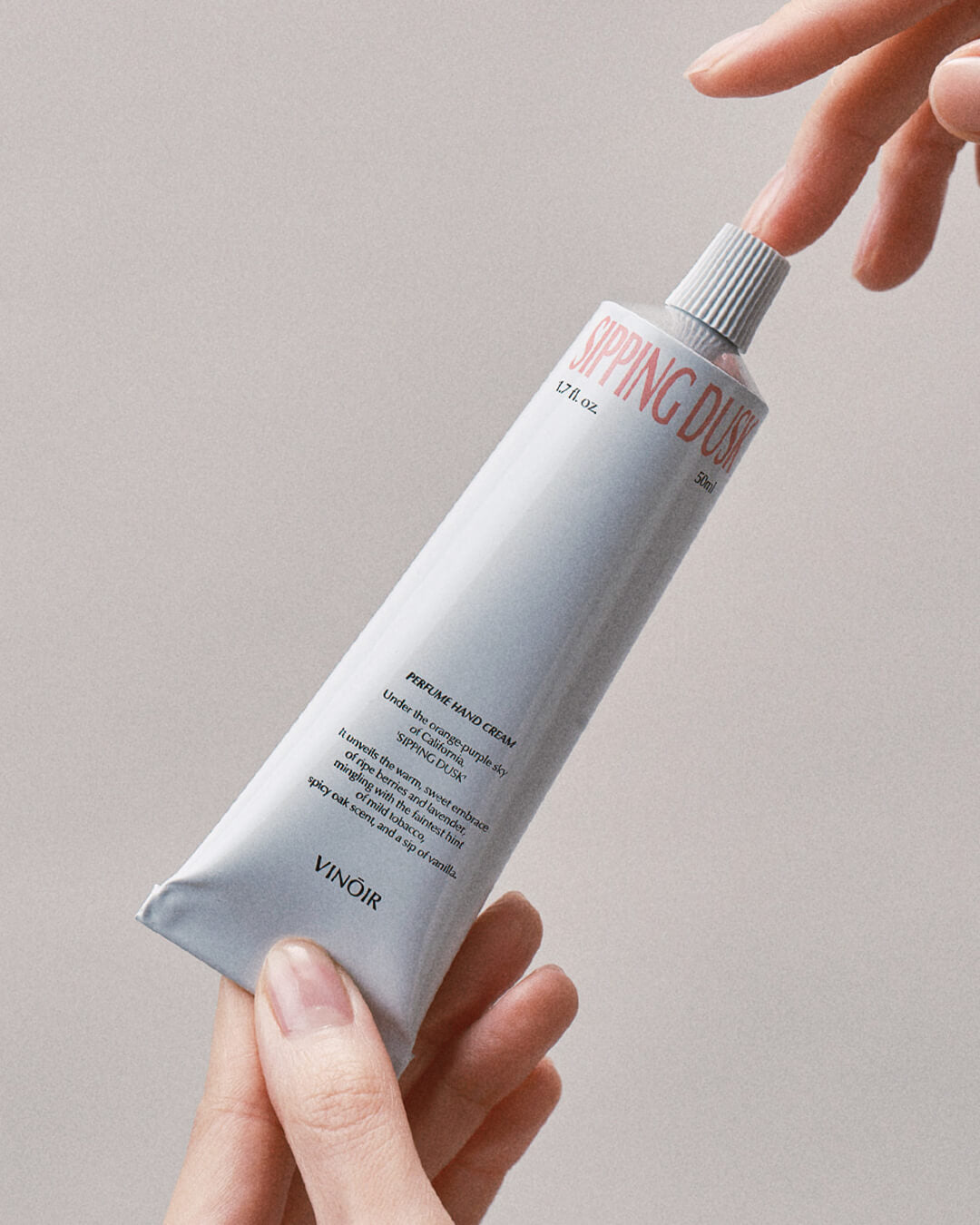 Ohlolly Korean Skincare Vinoir Decanting Hand Cream | Sipping Dusk. Scented moisturizer for dry hands. Hands holding Tube. Closeup.