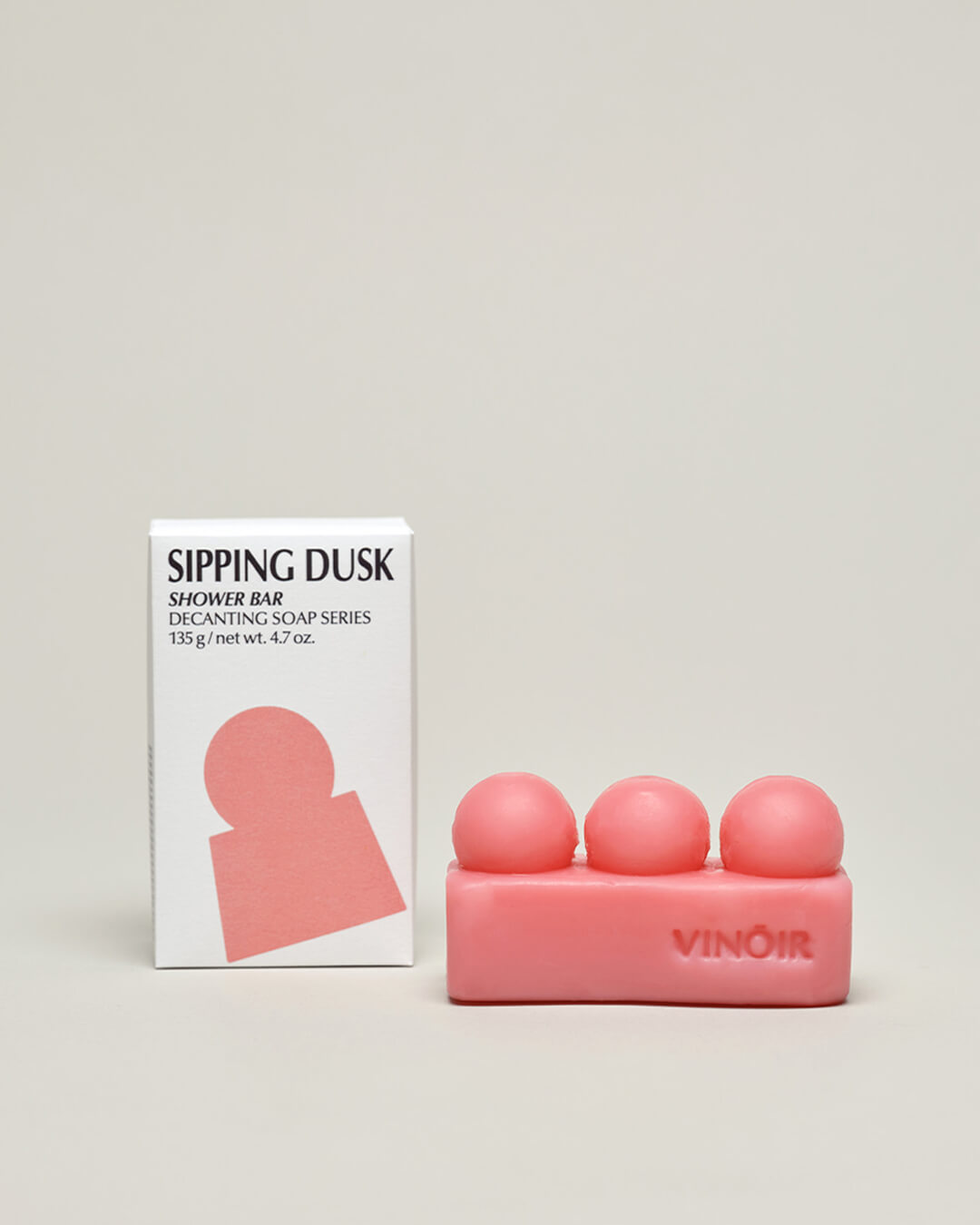 Vinoir Sipping Dusk decanting shower bar with rich pink color and natural ingredients. Box and product on tabletop.