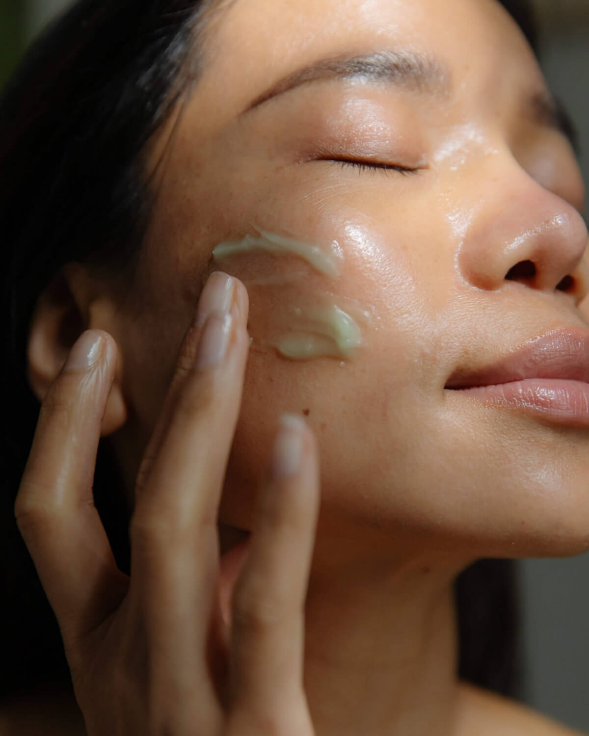 Close-up of a woman applying WYLYS Phyto Green Cleansing Balm to her cheek for a glowing complexion.