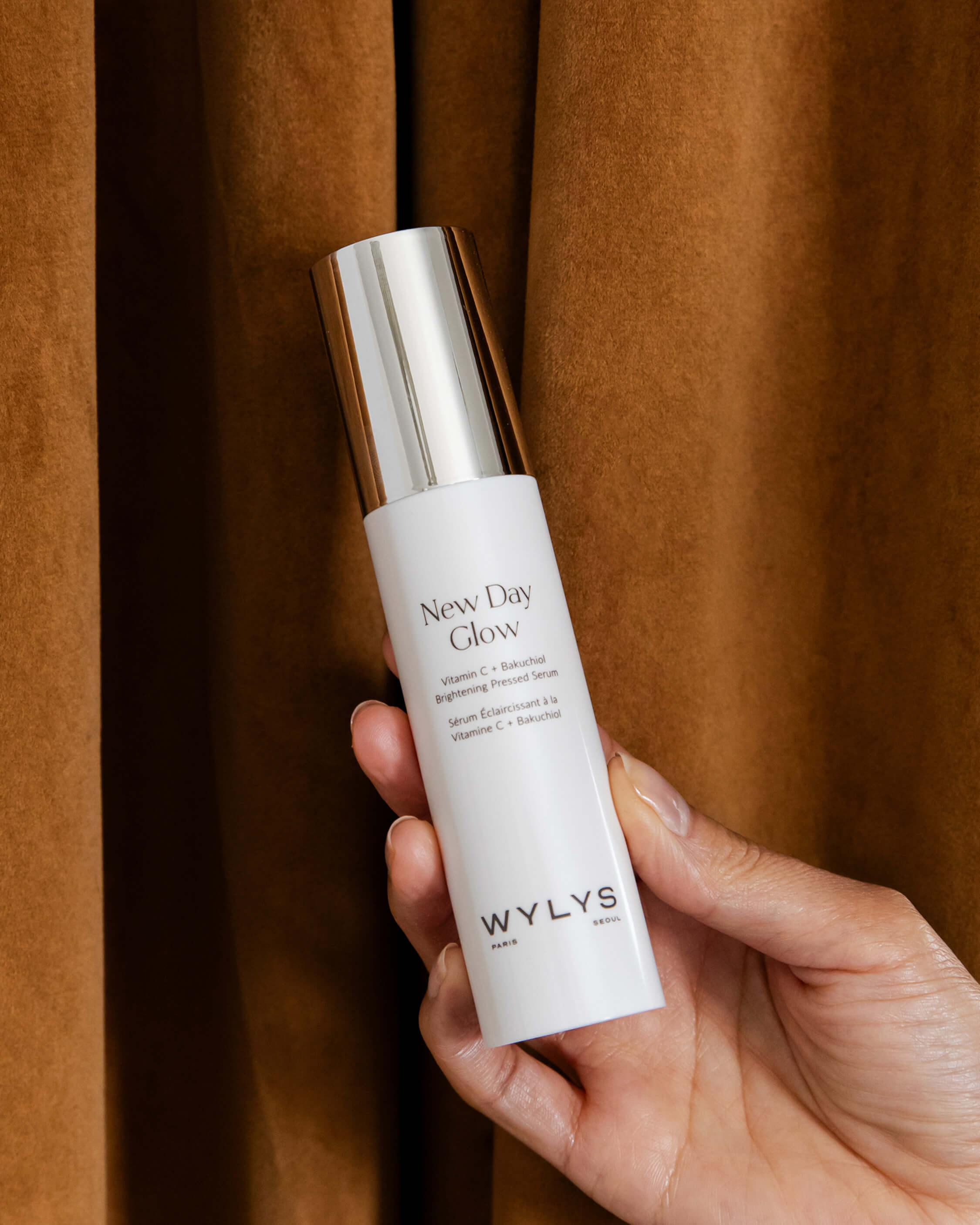 WYLYS New Day Glow Vitamin C Bakuchiol Brightening Serum Cream Plant-based retinol alternative pressed serum type, multipurpose serum and moisturizer in one. Made in Korea. K-beauty Clean beauty Bottle in Hand Curtain in back