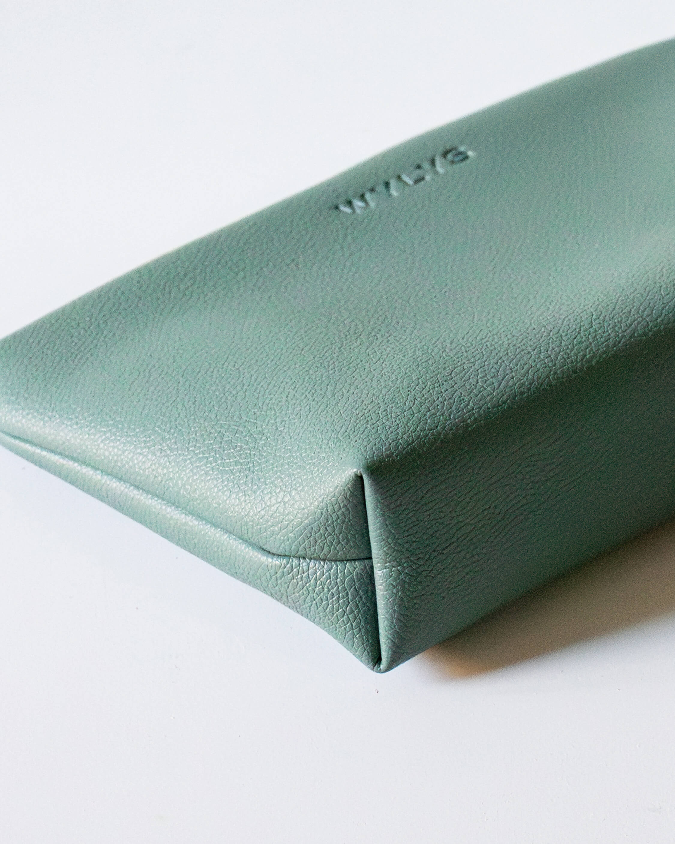 Wylys Sage Verte Makeup Bag – Soft Vegan Leather Pouch for Skincare & Makeup, Metal Zipper & Lining. Shows closeup of structure, stitching on bottom. Pebble texture of vegan leather.