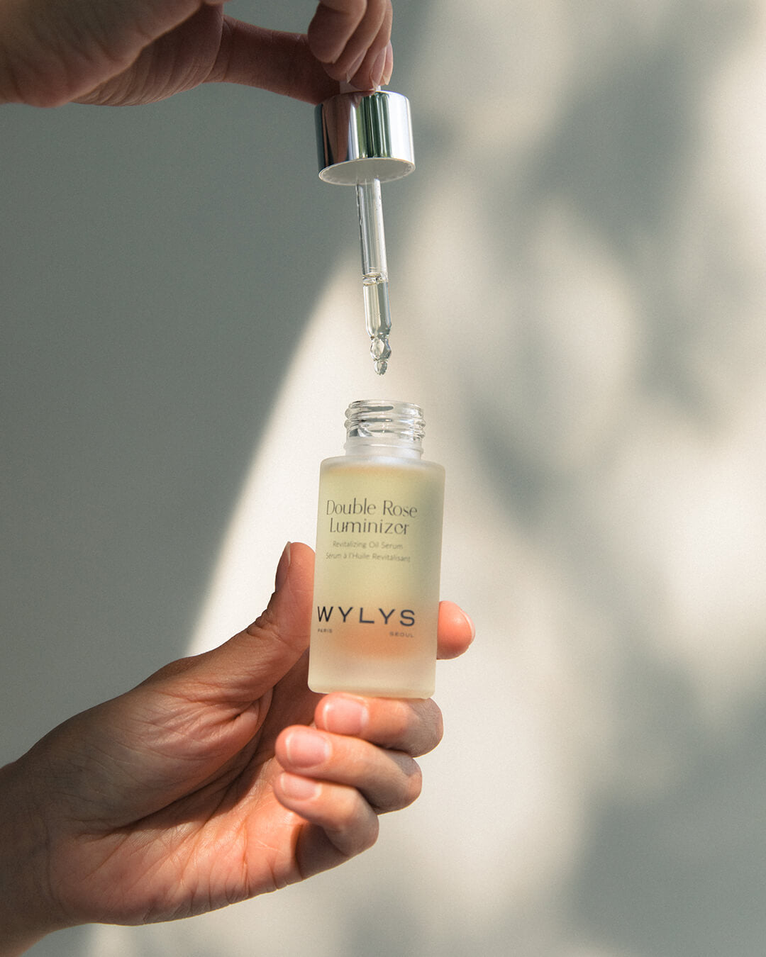 WYLYS Double Rose Luminizer Bottle in Hand When You Love Your Skin Texture dropping into bottle. Luxury vegan cruelty free oil blend made in France. Multipurpose oil, serum, makeup booster in one.