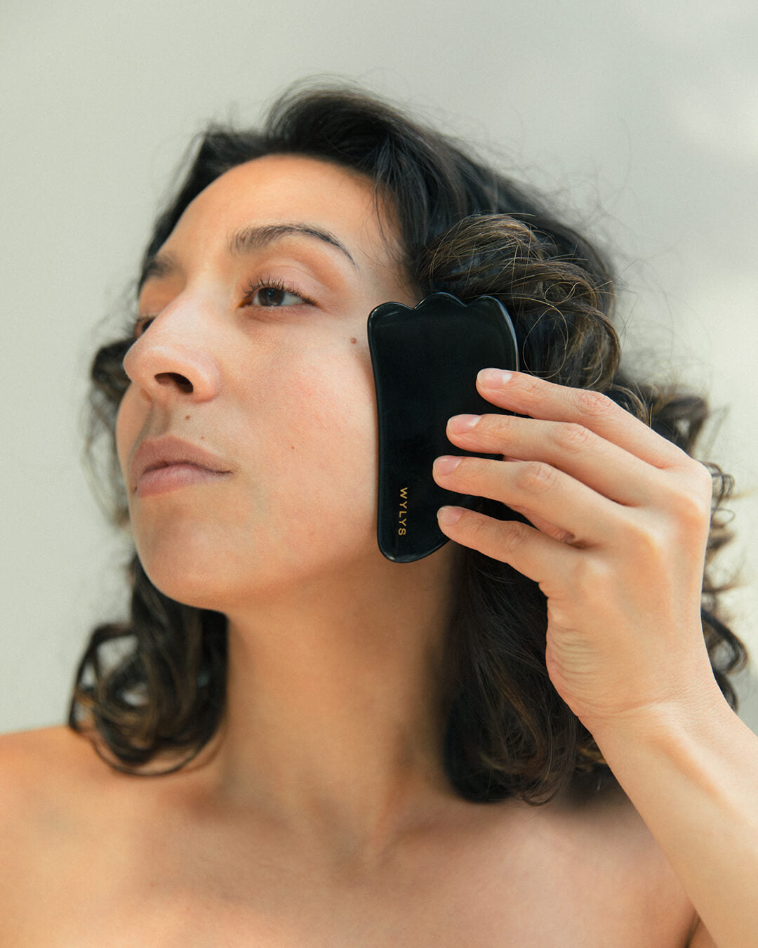 Ohlolly Korean Skincare Online Shop Wylys Black Obsidian Gua Sha + Face Roller Set, 100% natural Sculpting and depuffing tools for facial massage, tension relief, and radiant skin. Gua Sha on Model's face. Demo.