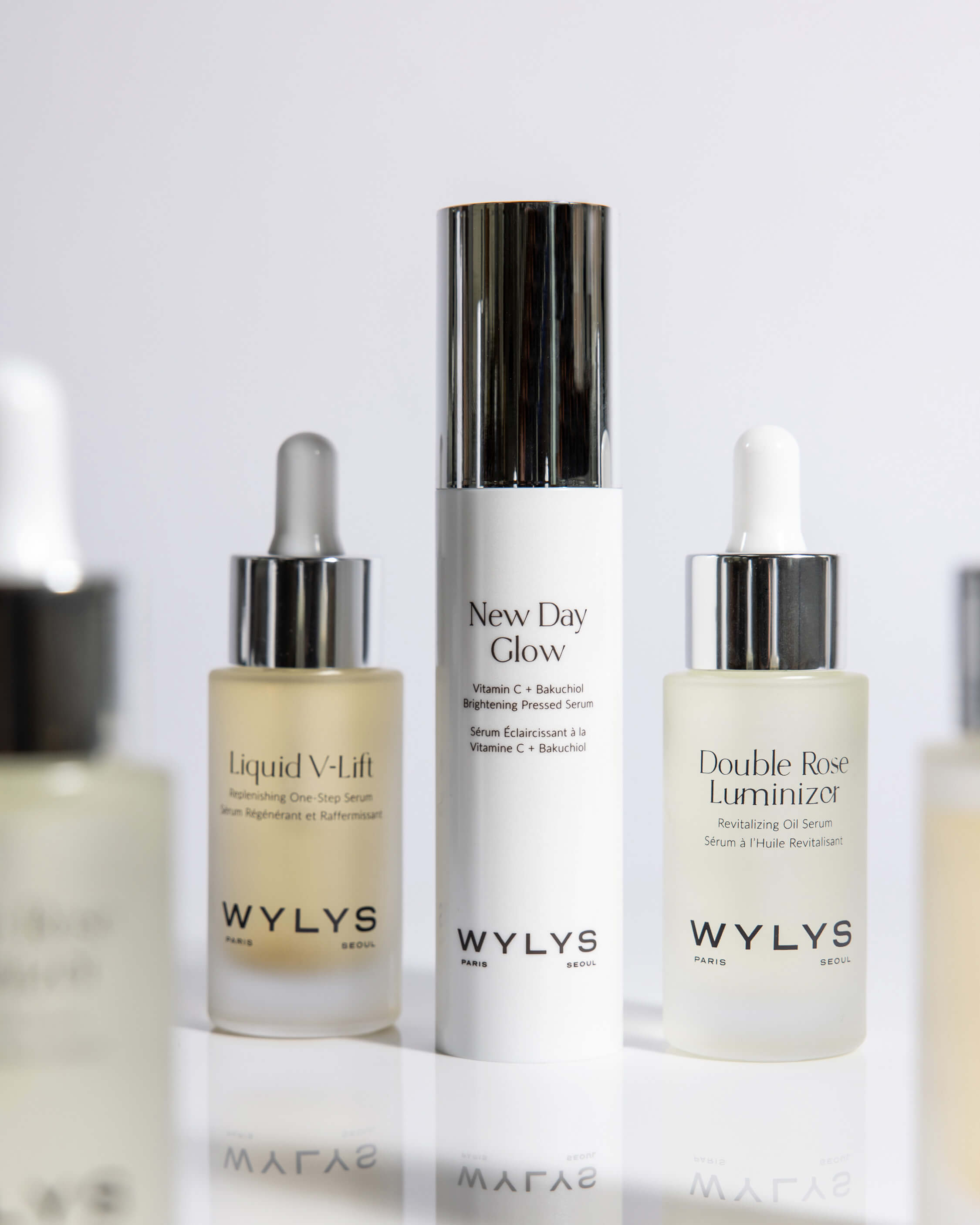Ohlolly K-Beauty Skincare WYLYS New Day Glow When You Love Your Skin Hero, Plant-based retinol alternative serum with bakuchiol, vitamin C, and niacinamide for bright, firm, and hydrated skin. Bottle next to Liquid V-Lift and Double Rose Luminizer. Group product photo. WYLYS best sellers.