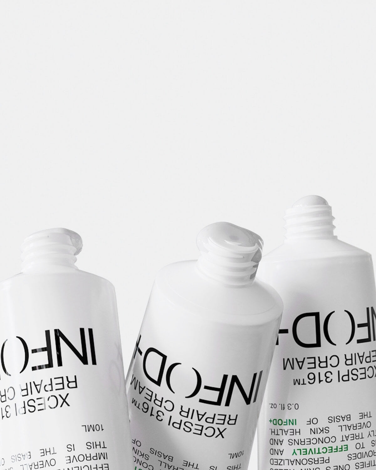 A low-angle close-up of three tilted tubes of InfoDPlus XCESPI 316™ Repair Cream, showing the white cream visibly at the opening of the middle tube.