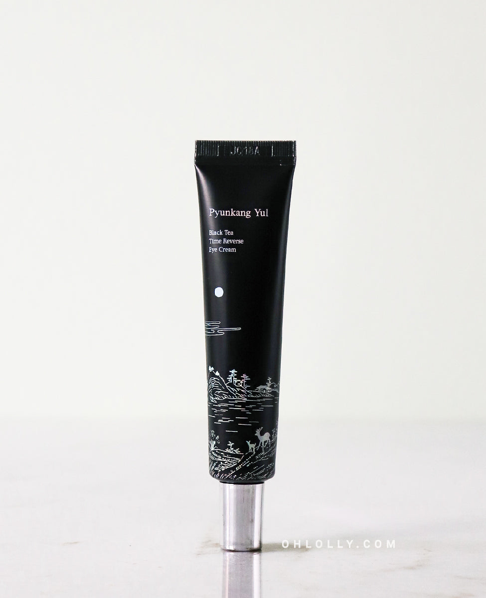 Front-on studio shot of the black Pyunkang Yul Black Tea Time Reverse Eye Cream tube standing upright. The tube features a white label and a small illustration of a deer and landscape, highlighting the product's premium anti-aging focus.