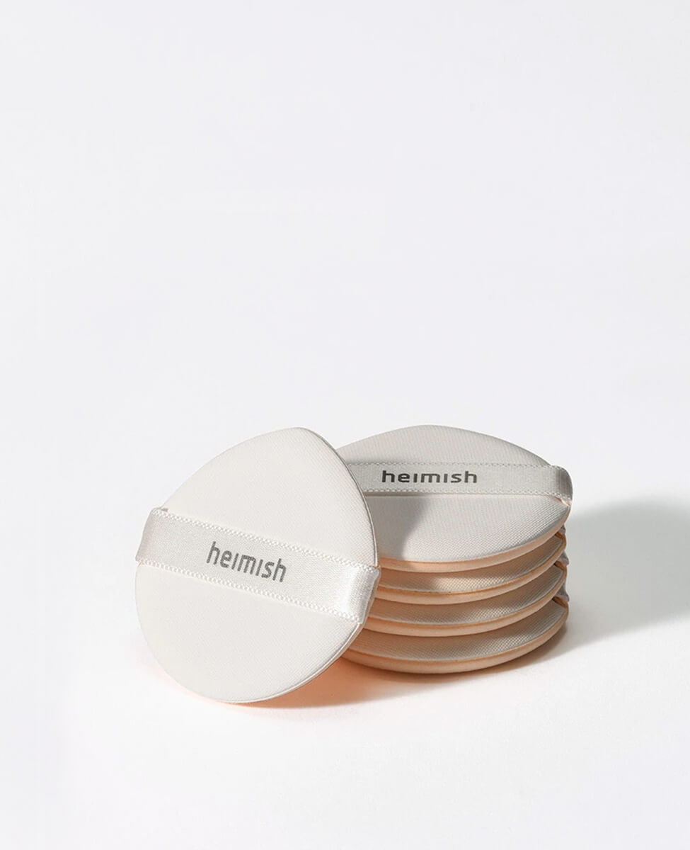 Stack of five Heimish Rubycell Cushion Puffs with the Heimish logo strap for smooth makeup application.