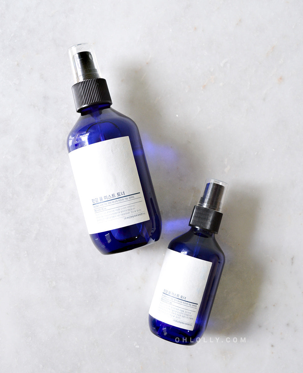Side-by-side product shot of the two sizes (200 ml and 100 ml) of the Pyunkang Yul Mist Toner. Both dark blue spray bottles have black caps and are standing on a plain white surface.