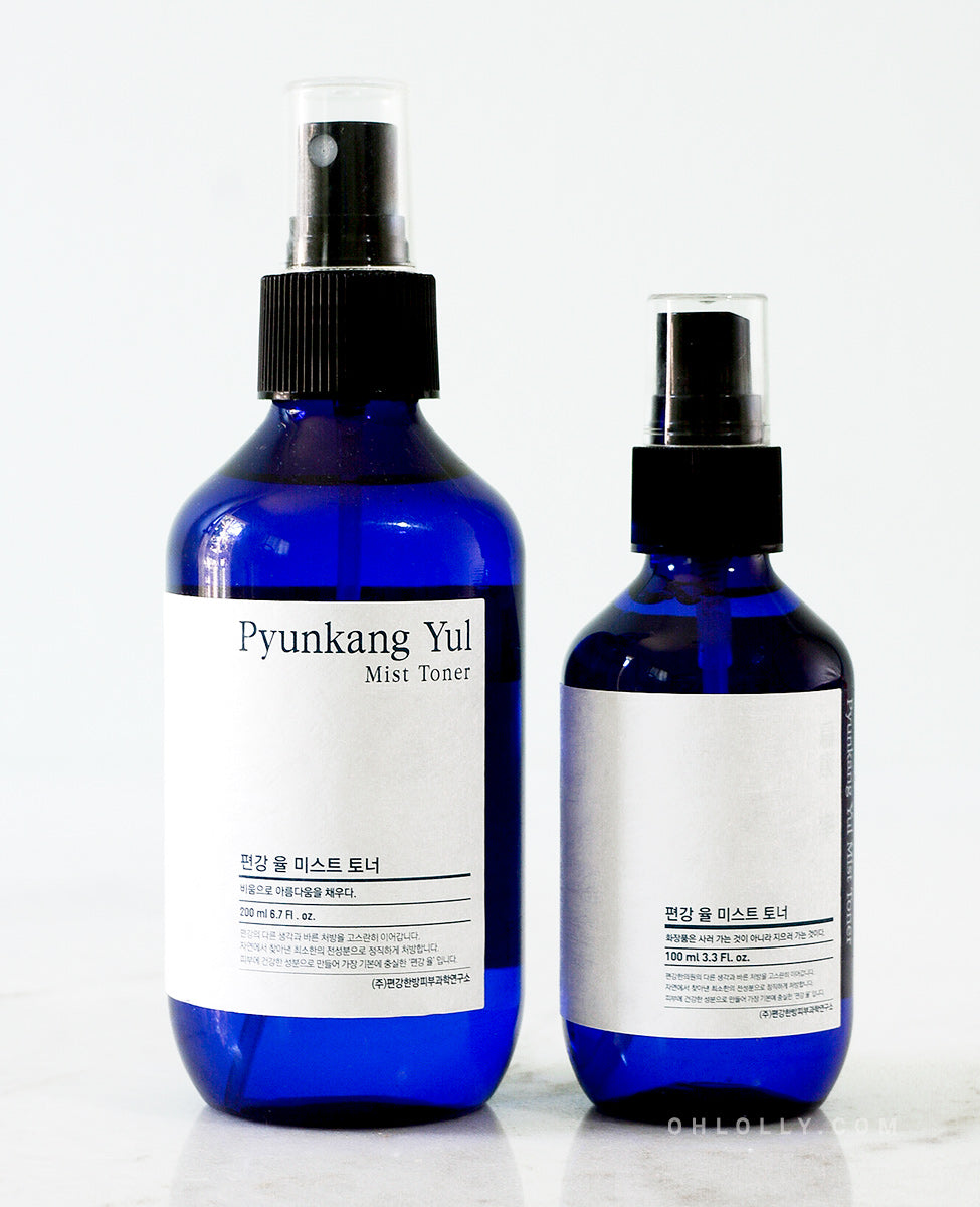 Close-up shot of side-by-side product shot of the two sizes (200 ml and 100 ml) of the Pyunkang Yul Mist Toner. Both dark blue spray bottles have black caps and are standing on a plain white surface.