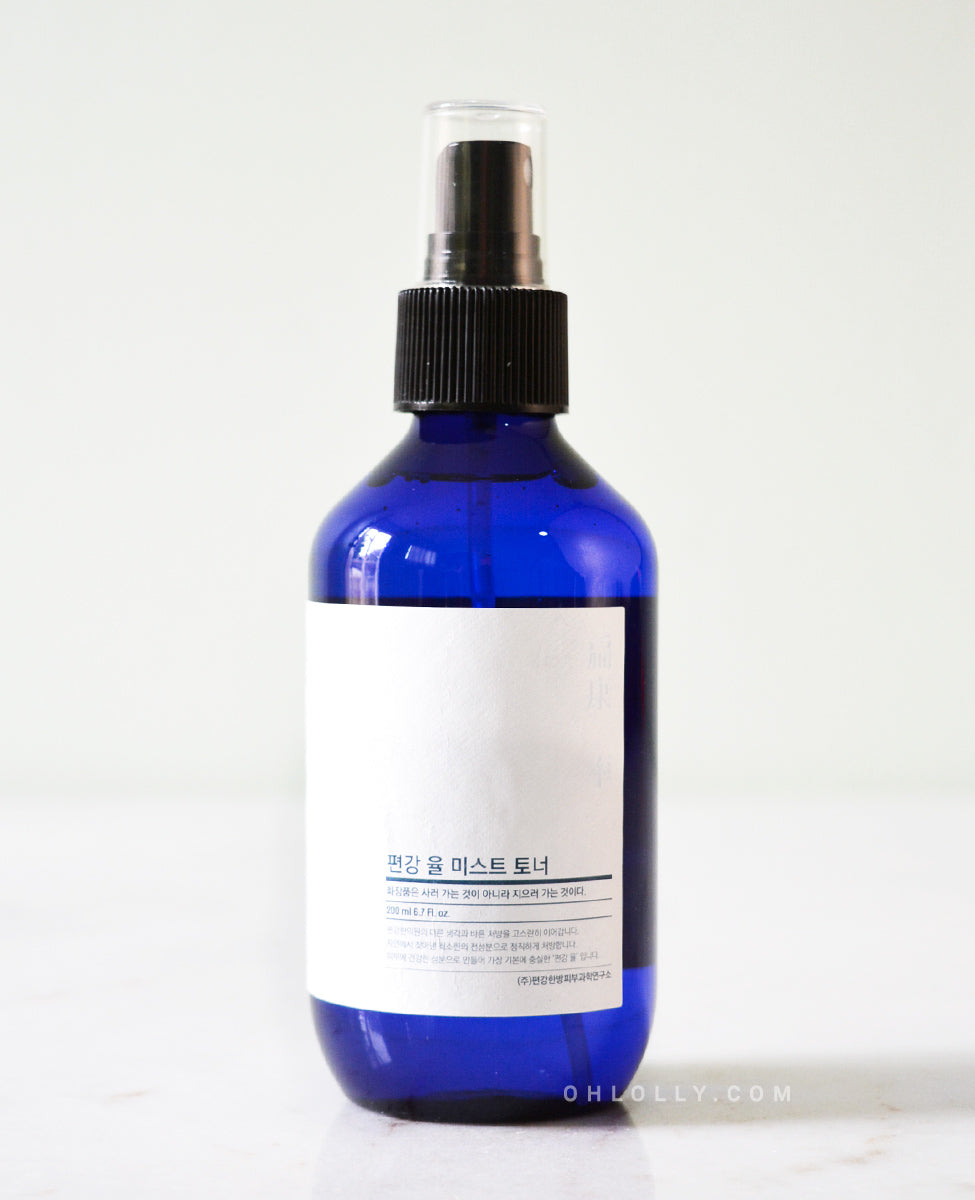 Close-up, detailed shot of the Pyunkang Yul Mist Toner's dark blue glass spray bottle, highlighting the white rectangular label and black spray nozzle.