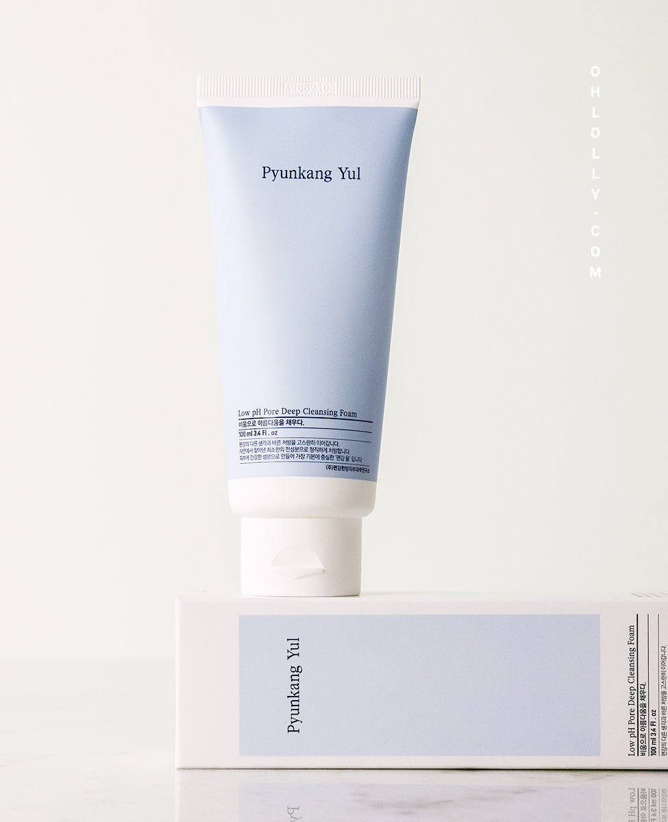 Studio shot of the Pyunkang Yul Low pH Pore Deep Cleansing Foam tube, standing on its white cardboard box. The light blue tube is slightly angled, clearly showing the product name and low pH formula on the label, against a pale background.