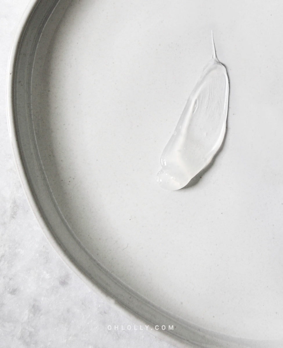 A small, white, translucent swipe of the Pyunkang Yul Peeling Gel on a smooth, curved, light gray plate, showcasing the product's soft gel texture.