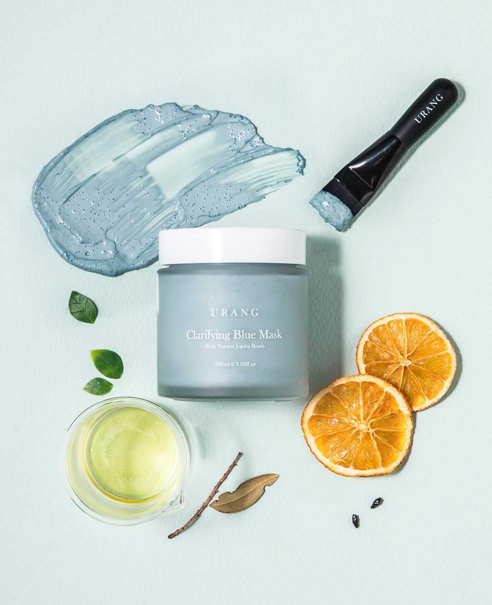 Flat lay of Urang Clarifying Blue Mask jar, showing the blue clay mask texture and application brush, emphasizing its soft clay and brightening, clarifying effect.