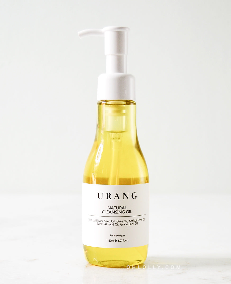 Urang Natural Cleansing Oil in a clear glass pump bottle, showing the bright yellow oil inside against a light gray background.