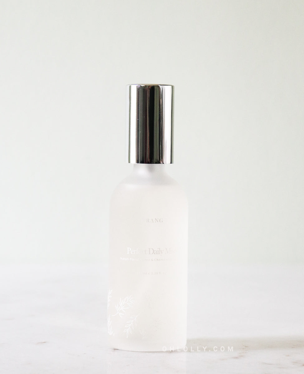 Urang Perfect Daily Mist in a frosted glass spray bottle with a shiny silver cap, standing on a light marble or stone surface.
