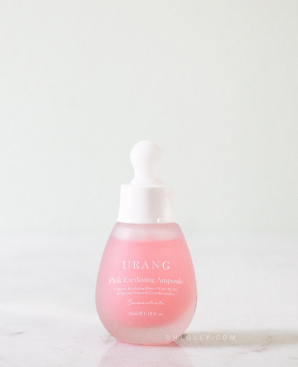 The Urang Pink Everlasting Ampoule in a frosted pink glass dropper bottle with a white cap, sitting on a white, slightly reflective marble surface.