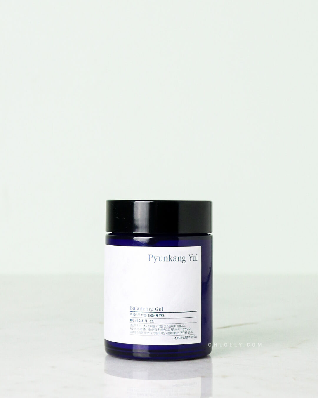 Front-on studio shot of the Pyunkang Yul Balancing Gel jar. The dark blue glass jar has a simple white label and stands upright on a pale background, emphasizing its unique honey-like texture and anti-aging benefits.
