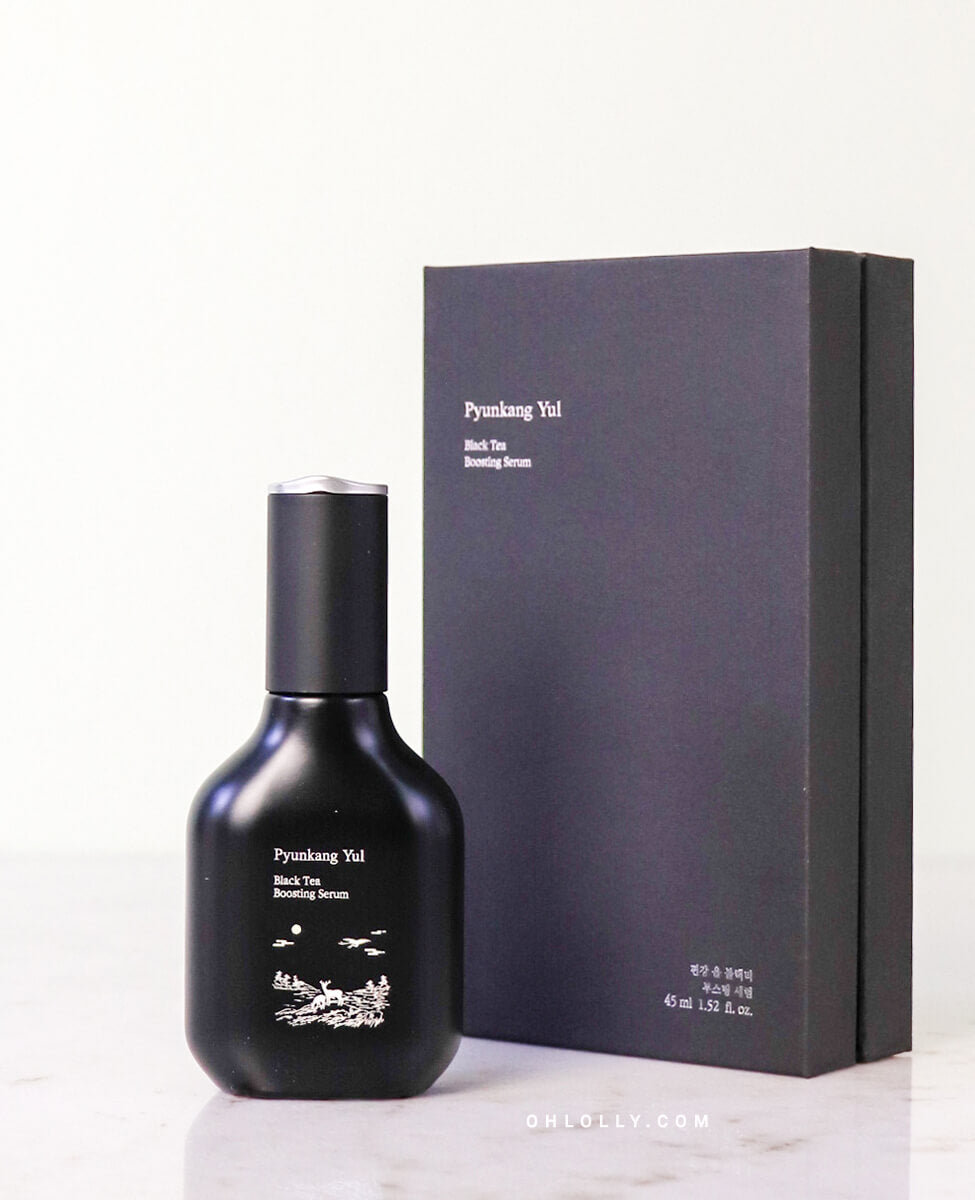 Front-on studio shot of the black Pyunkang Yul Black Tea Boosting Serum glass bottle with its dropper cap, standing next to its black, matte outer box, emphasizing the product's premium, minimalist, and anti-aging focus.