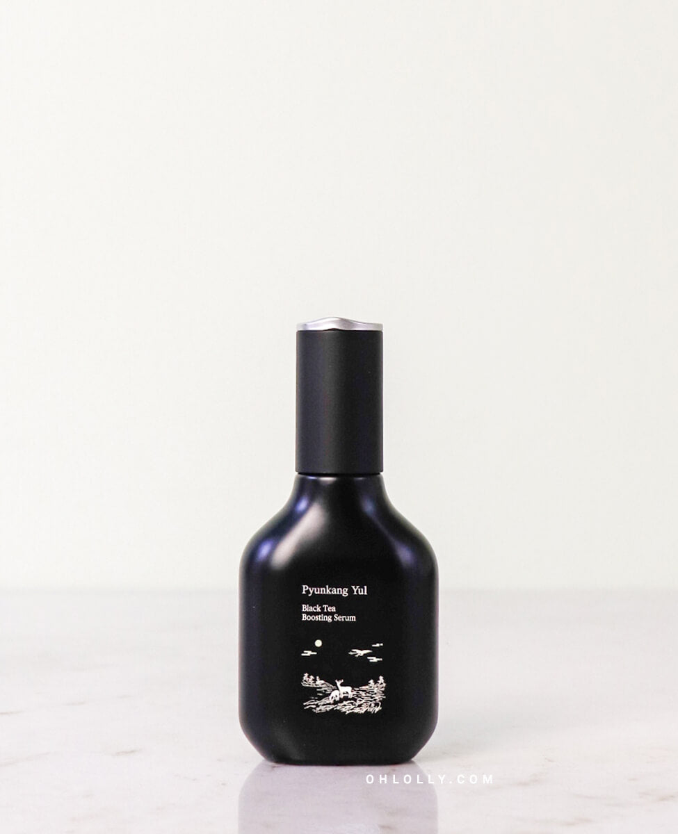 Front-on studio shot of the Pyunkang Yul Black Tea Boosting Serum dark blue glass bottle with its dropper cap. The bottle is standing on a pale surface, highlighting its elegant, anti-aging focused packaging.