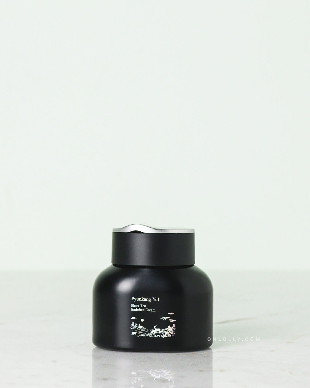 ront-on studio shot of the black Pyunkang Yul Black Tea Enriched Cream jar with its black lid. The jar features a small white label with the product name and stands on a pale surface, emphasizing its rich, anti-aging formula.