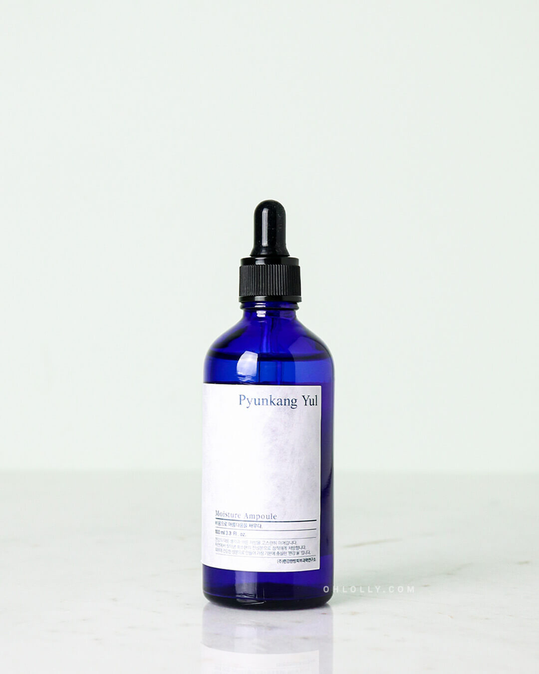 Studio shot of the Pyunkang Yul Moisture Ampoule. The rich, honey-like gel is contained in a dark blue glass jar, with the dropper resting on the rim, against a pale white background.