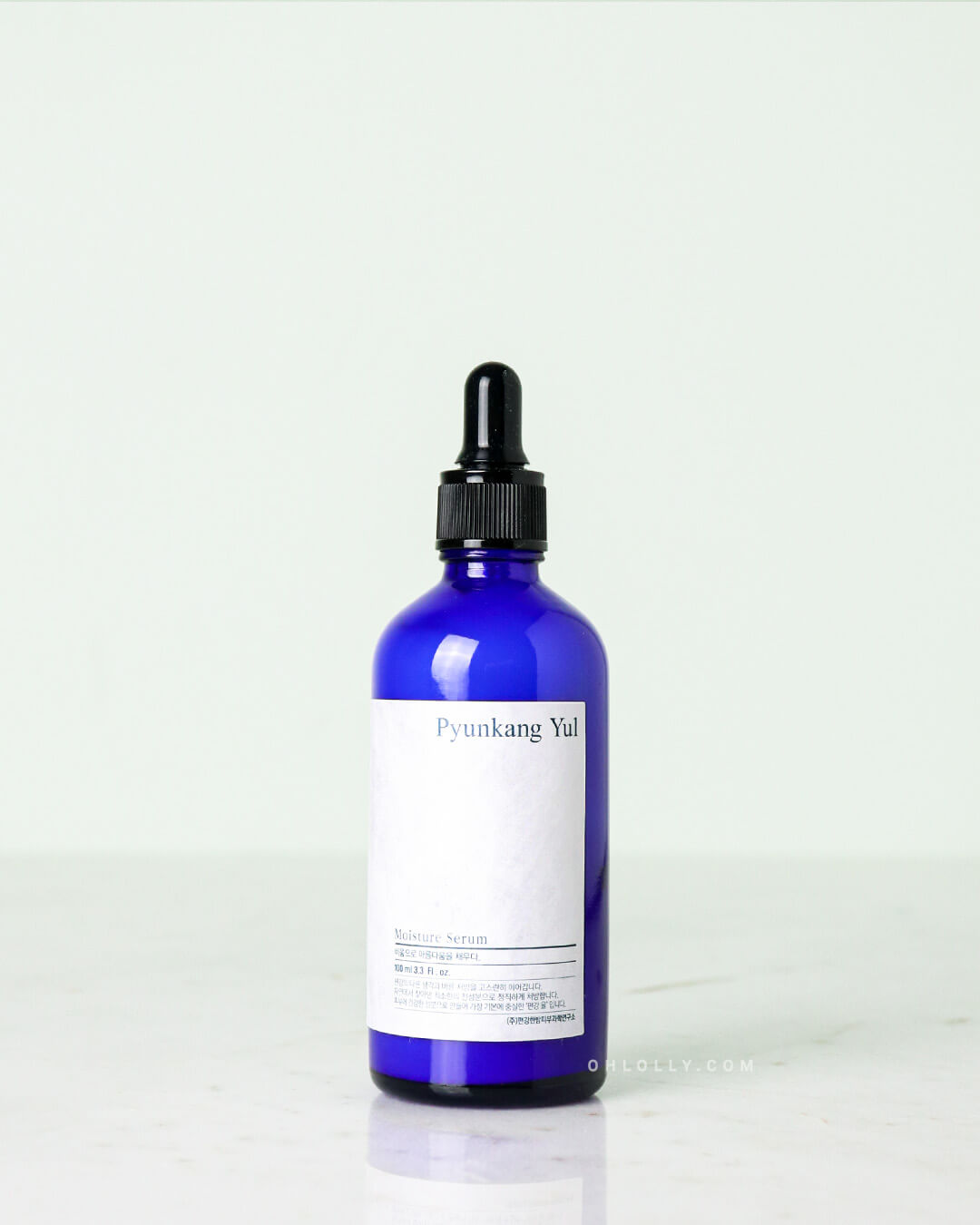 Studio shot of the Pyunkang Yul Moisture Serum. The dark blue glass dropper bottle has a black cap and is centered on a clean, light surface, clearly displaying the white rectangular label.
