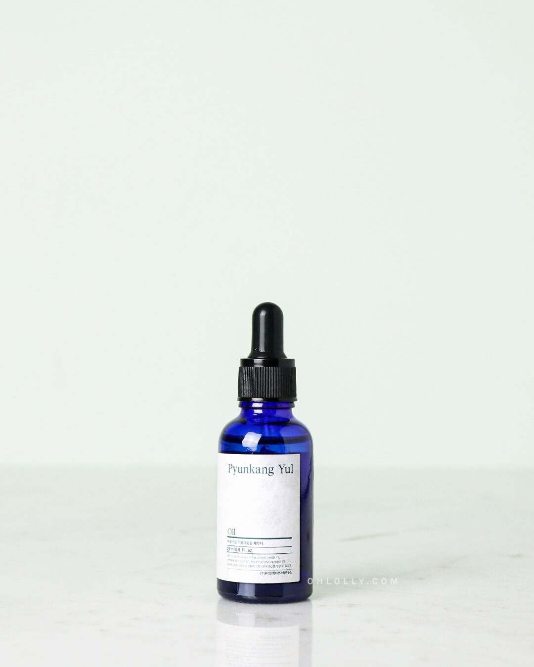 Studio shot of the Pyunkang Yul Oil. The small, dark blue glass dropper bottle with a black cap is centered on a light, neutral background, clearly displaying the white rectangular label.