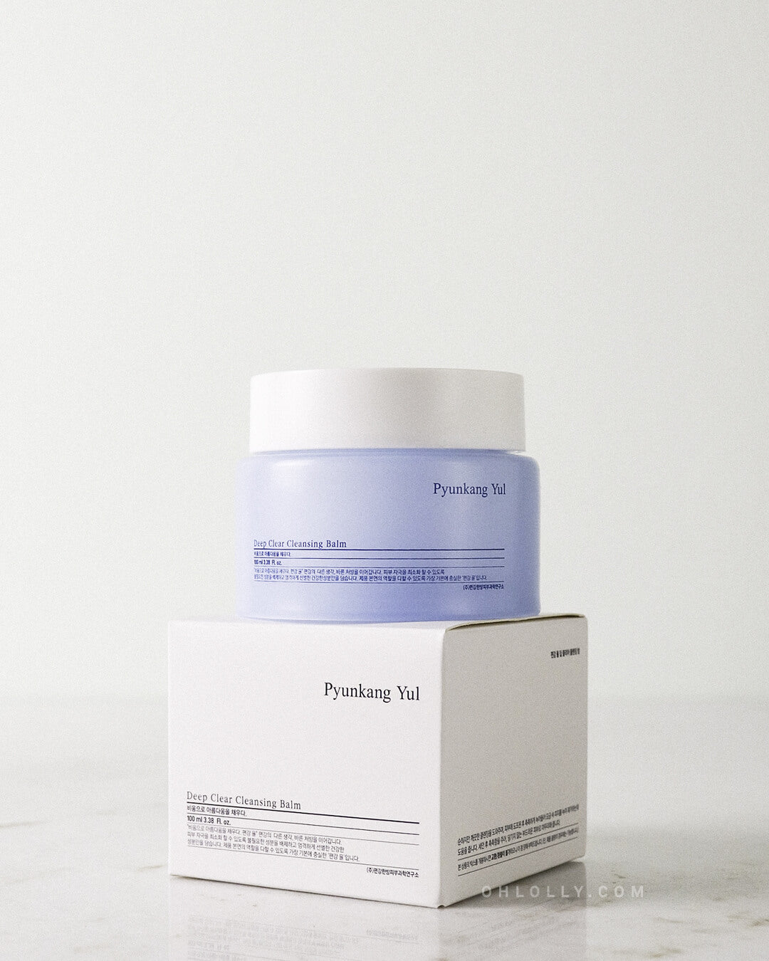 Front-on studio shot of the light blue Pyunkang Yul Deep Clear Cleansing Balm jar standing on its white outer box. The image emphasizes the product's clean, minimalist packaging and its barrier-boosting, hydrating formula for a first cleanse.