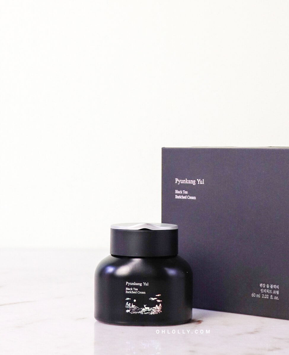 Front-on studio shot of the black Pyunkang Yul Black Tea Enriched Cream jar standing in front of its black, matte outer box. The image emphasizes the product's luxurious anti-aging formula and premium, minimalist packaging.