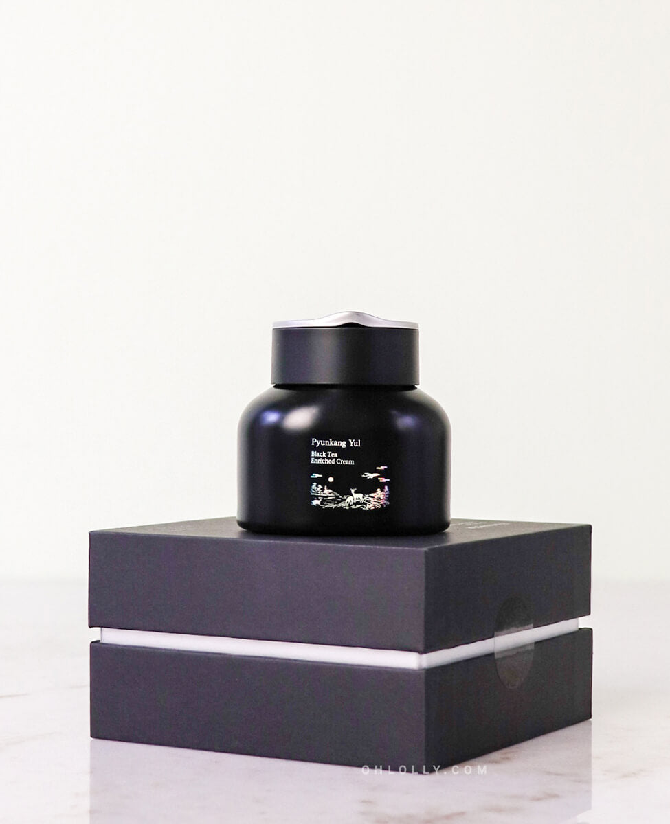 Front-on studio shot of the black Pyunkang Yul Black Tea Enriched Cream jar standing on its black outer box. The image emphasizes the product's premium, anti-aging focus with fermented black tea and peptide ingredients.