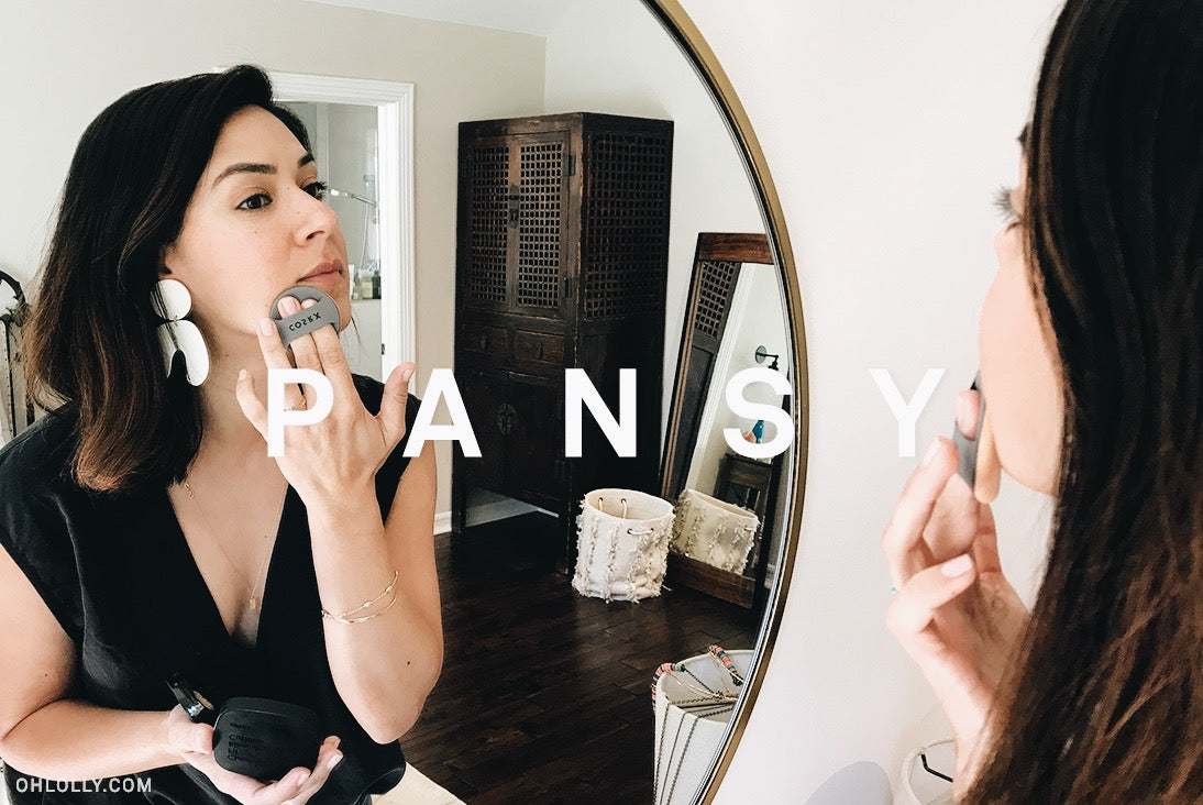 Smiling woman with dark hair and a black top. Overlay text: PANSY. Minimalist beauty and fashion portrait.