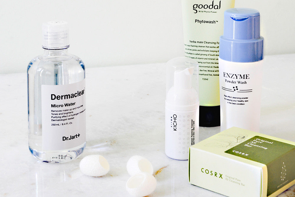 Assortment of cleansers and exfoliators, including Dr. Jart+ Micro Water, an Enzyme Powder Wash, and a COSRX Cleansing Bar.