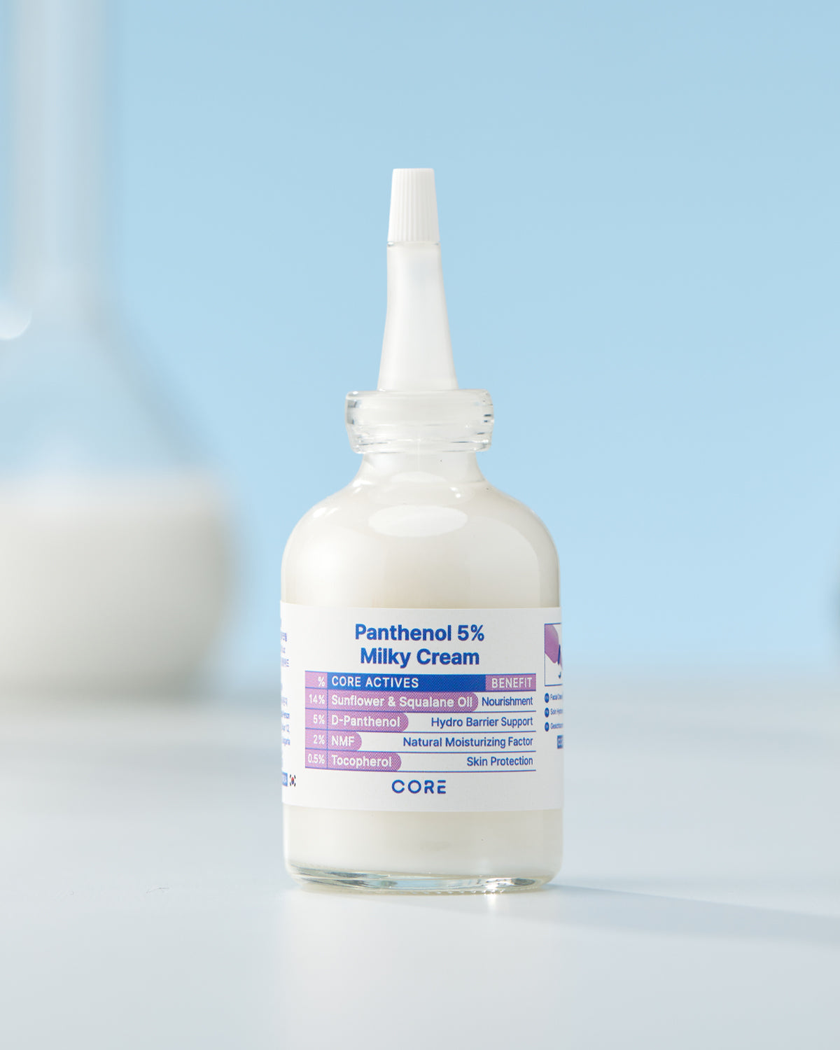 The bottle of Panthenol 5% Milky Cream is shown in a clean, studio setting against a light blue background.