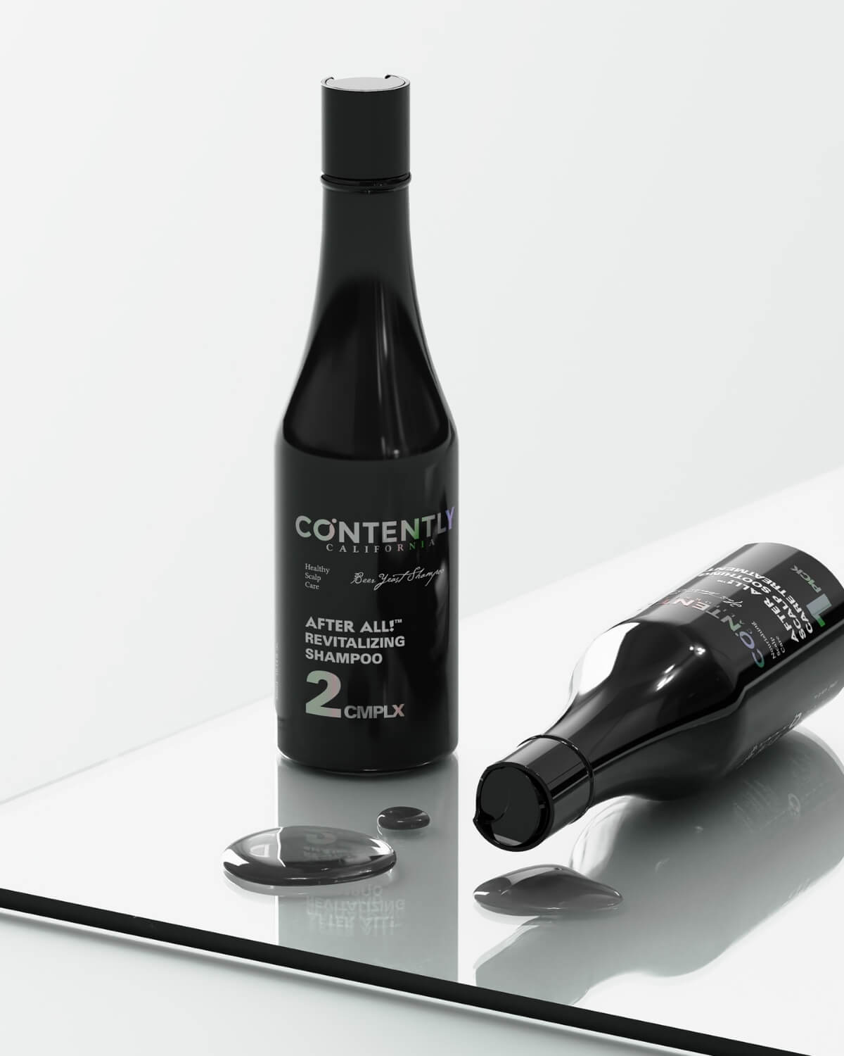 One upright and one horizontal bottle of the Revitalizing Shampoo on a glass surface, with two drops of dark-colored shampoo product spilled on the surface.