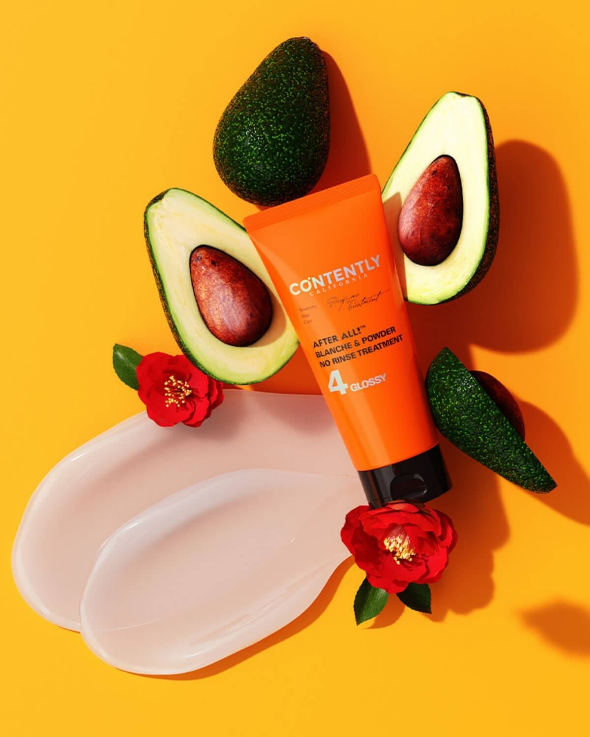 An overhead shot showing the orange treatment tube surrounded by two halved avocados. Two thick smears of the light pink/white product cream are visible in the foreground, all set against a vibrant yellow background.