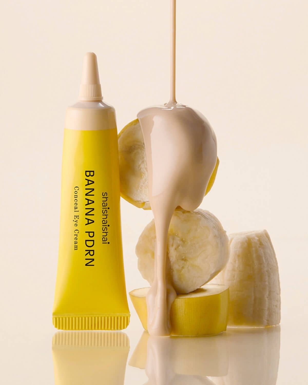 Light shade of shaishaishai Banana PDRN Conceal Eye Cream being poured over fresh banana chunks.