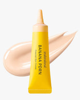 A yellow tube of shaishaishai Banana PDRN Conceal Eye Cream with a pale, light beige cream swatch in the background.