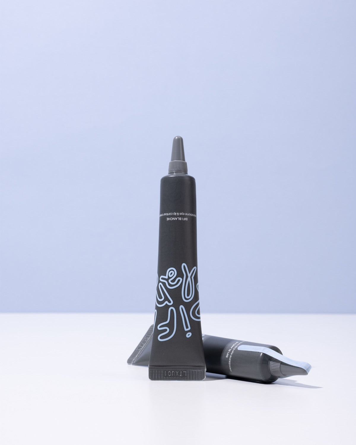 Two tubes of Bifi Blanche Microbiome Eye and Lip Cream arranged on a white surface with a light blue backdrop.