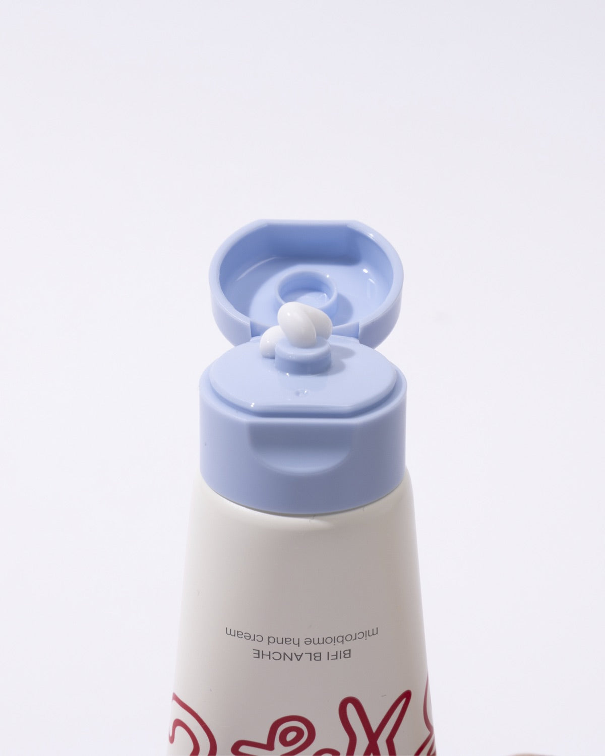 Close-up of an open light blue flip-top cap dispensing white Bifi Blanche Microbiome Hand Cream.