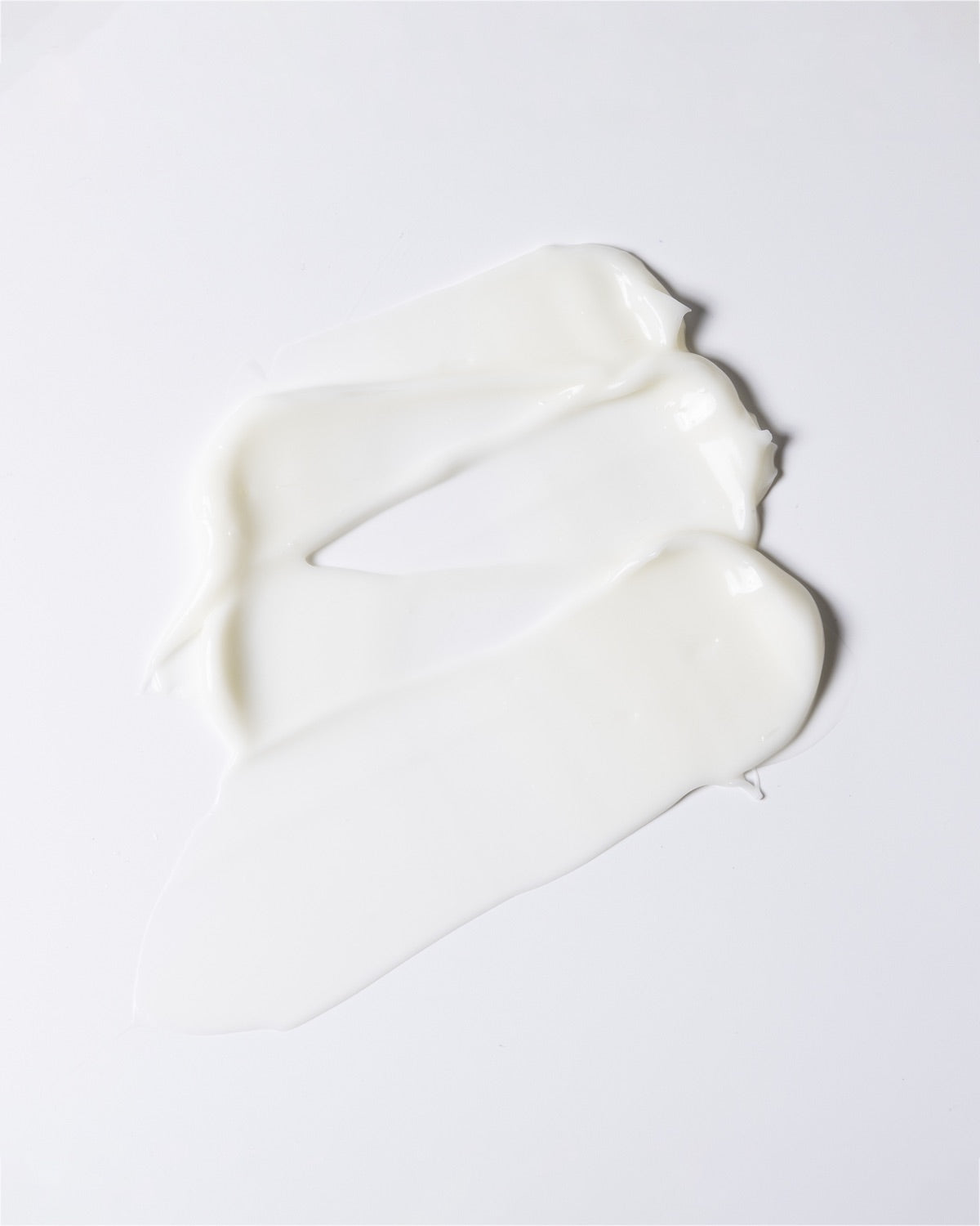 Smooth, thick swipe texture of white face moisturizer cream on a clean white background.