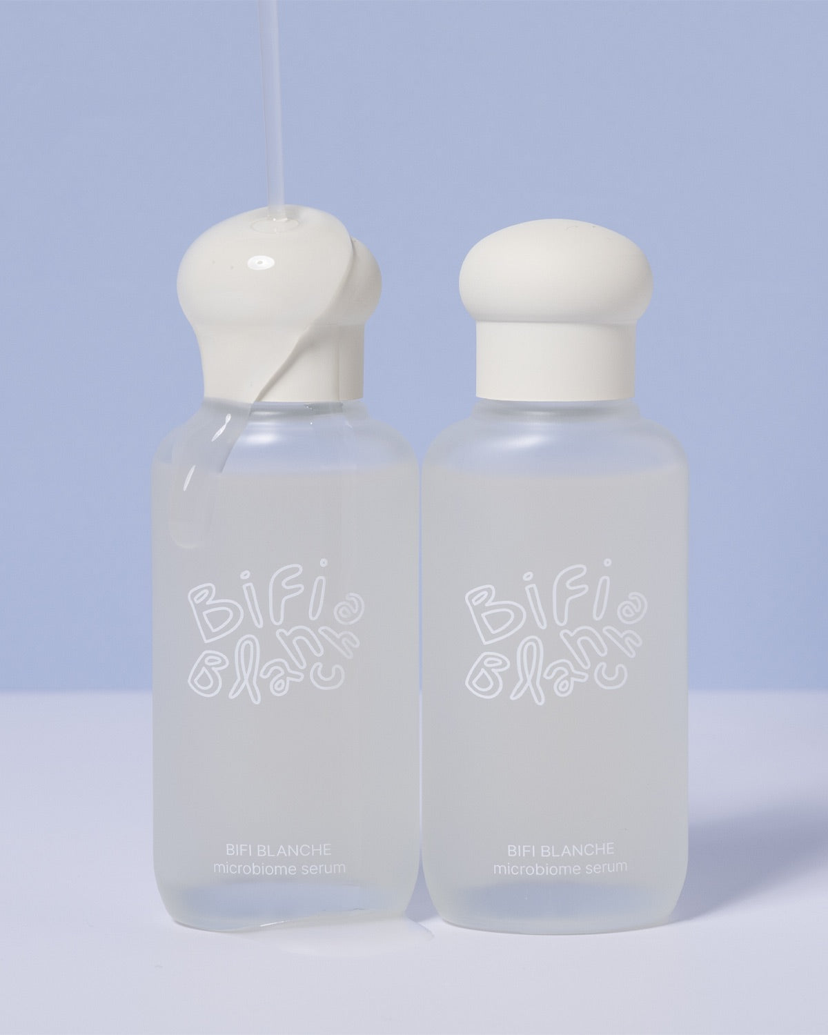 Two bottles of Bifi Blanche Microbiome Serum with clear liquid dripping over one of the caps.