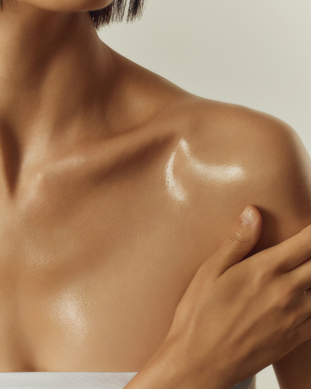 Glowy, hydrated skin on a person's shoulder from Huxley nourishing body oil.