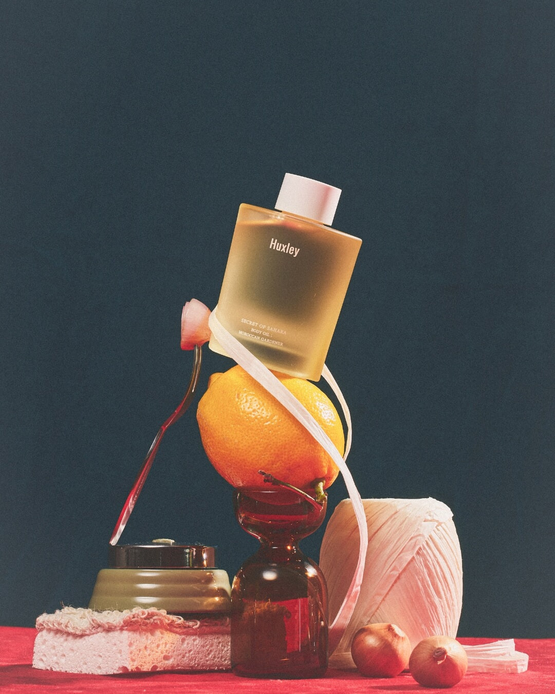 Editorial product shoot of Huxley Moroccan Gardener body oil bottle resting on a lemon.