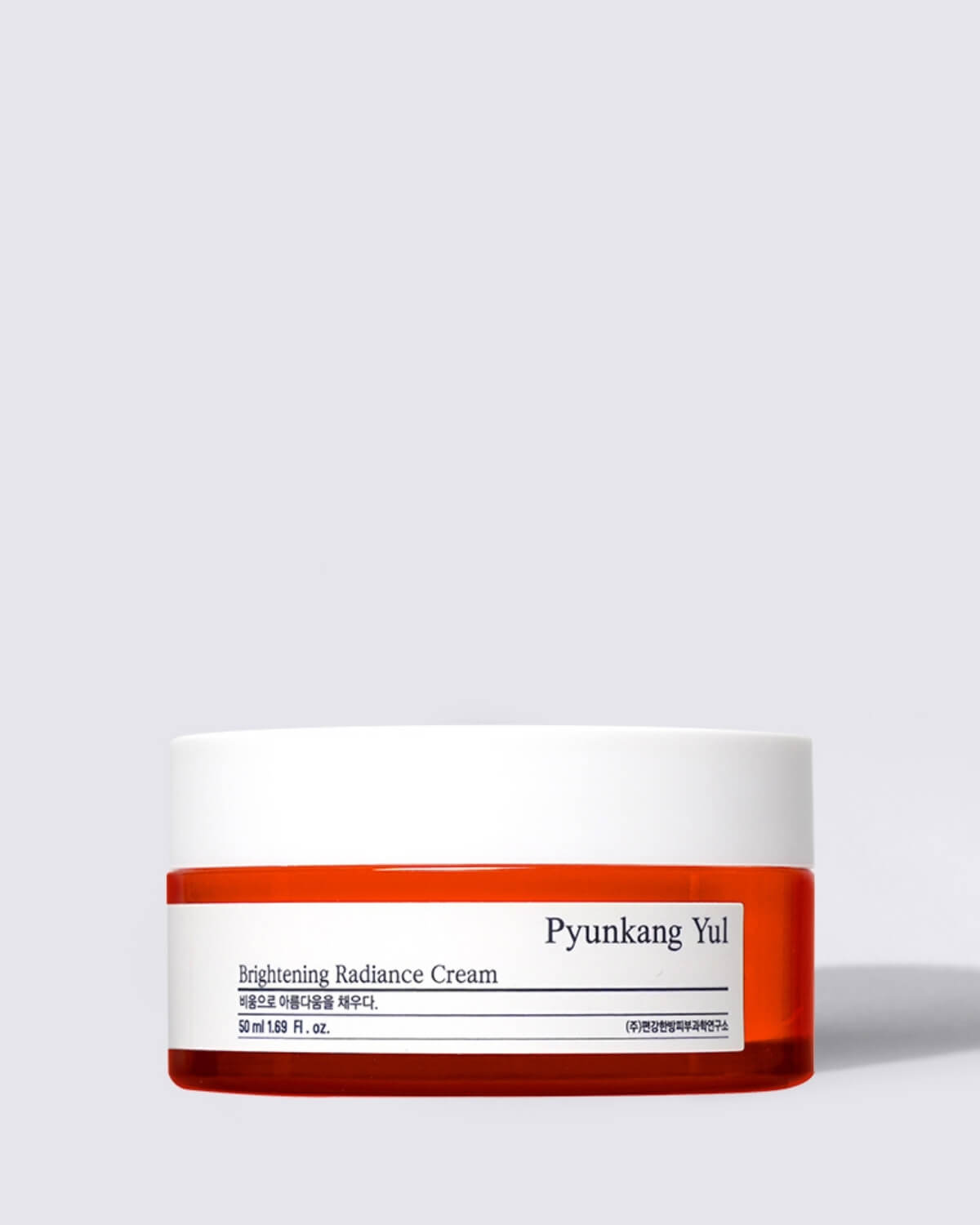 A clear, individual studio shot of the Pyunkang Yul Brightening Radiance Cream in its low, wide jar with a white lid and an orange-red base.