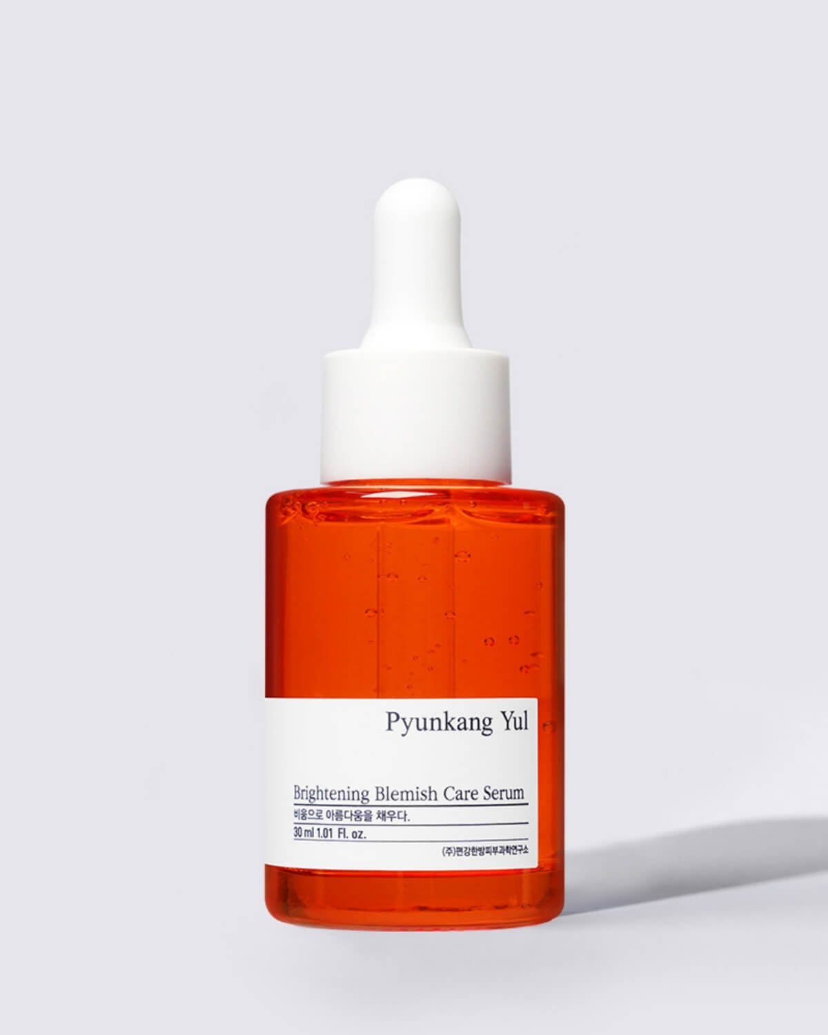 A close-up, individual shot of the Pyunkang Yul Brightening Blemish Care Serum in its small, orange-red glass bottle with a white dropper lid.
