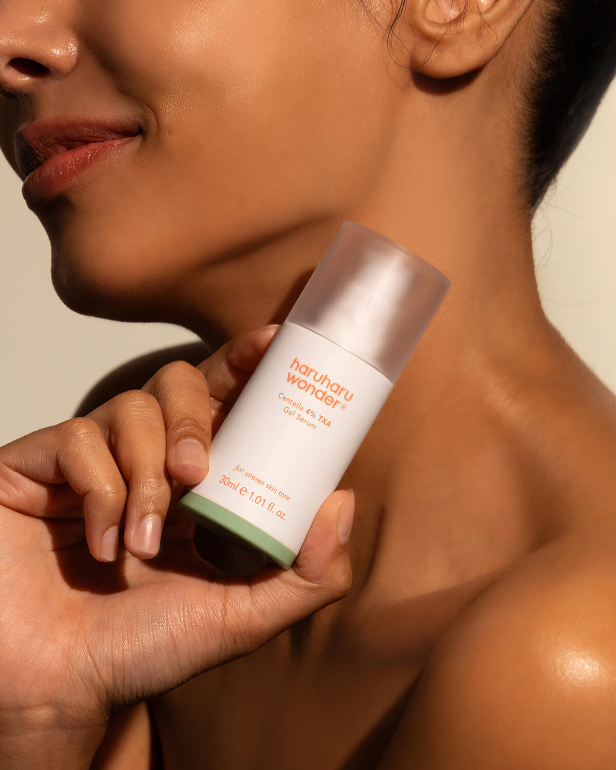 Model holding Haruharu Wonder Centella 4% TXA Gel Serum bottle near glowing skin.