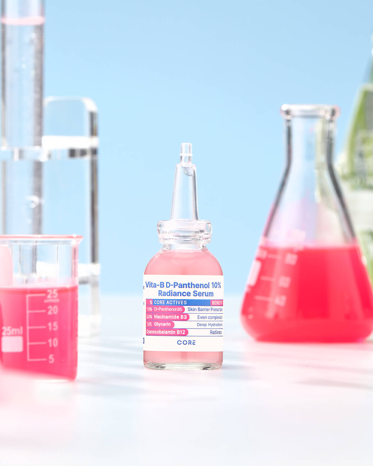 The bottle of pink radiance serum is centered in a laboratory setting, flanked by glassware including a beaker with a pink liquid and a tall flask.